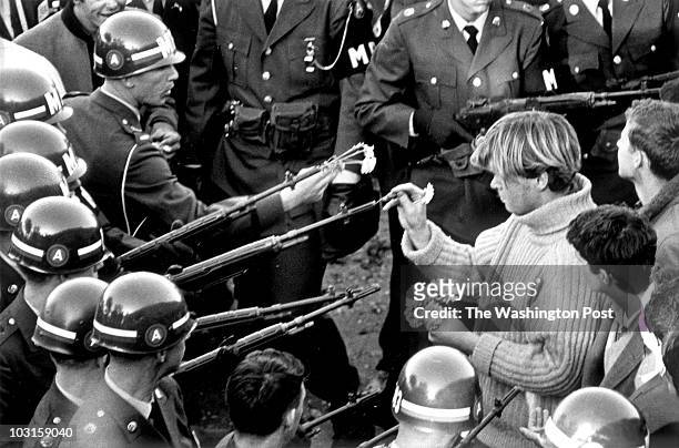 George Harris sticks carnations in gun barrels during an antiwar demonstrator at Pentagon in 1967. They tried flower power on MPs blocking the...