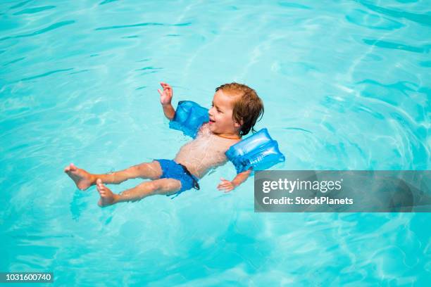 beauty little boy floating at the swimming pool - boys water wings stock pictures, royalty-free photos & images