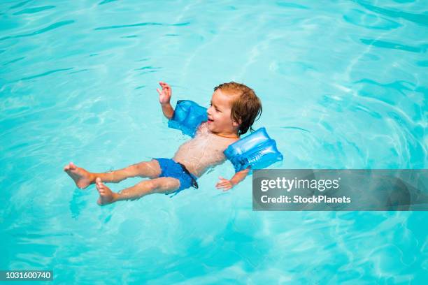 beauty little boy floating at the swimming pool - arm floats stock pictures, royalty-free photos & images