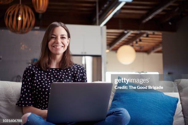 smiling businesswoman sitting on sofa in creative office - businesswoman couch fotografías e imágenes de stock