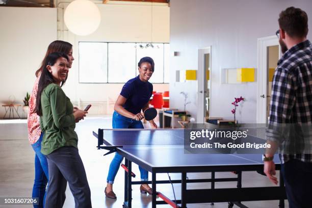 coworkers playing table tennis in office - ping pong fotografías e imágenes de stock