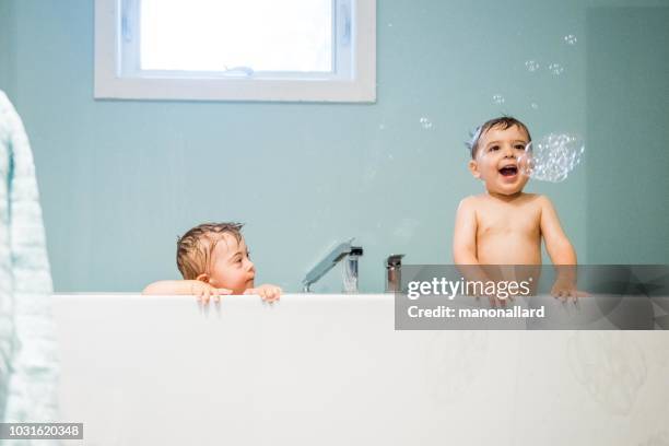 down-syndrom süßer junge in der badewanne mit seinem bruder - brothers bathroom stock-fotos und bilder