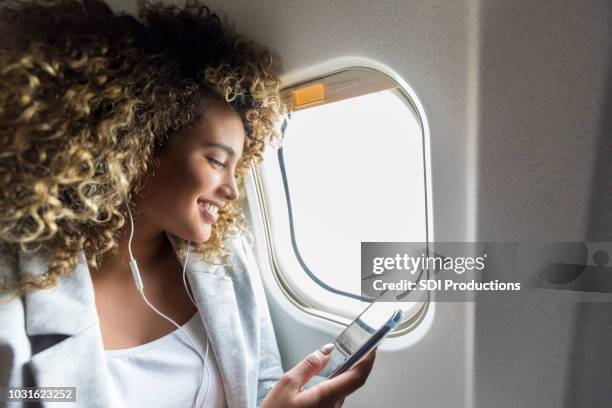 woman choose music during flight - mobile on plane stock pictures, royalty-free photos & images