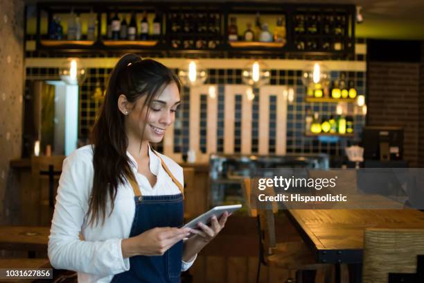 female owner of a bar looking at her tablet computer and smiling - waiter using digital tablet stock pictures, royalty-free photos & images