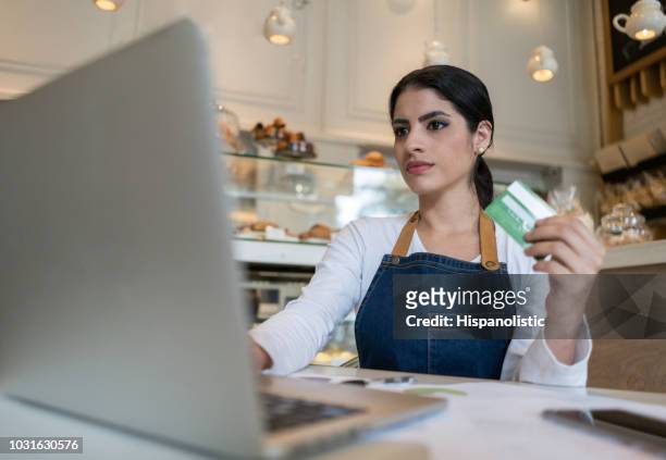 ernstige vrouwelijke ondernemer van een bakkerij online winkelen met haar creditcard - business credit card stockfoto's en -beelden