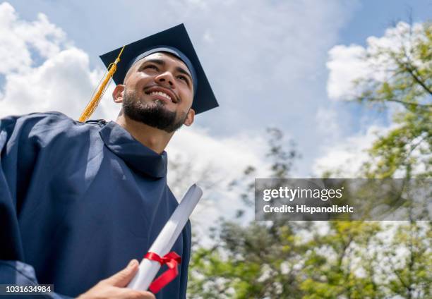 proud young man holding his diploma on graduation day looking very happy - secondary school certificate stock pictures, royalty-free photos & images