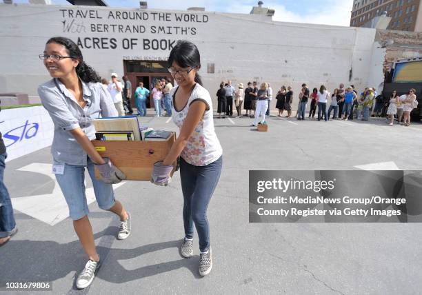 Joy Contreras, left, and Linda Nguyen help a customer carry their books during Acres of Books' last hurrah in Long Beach, CA on July 10, 2010. The...