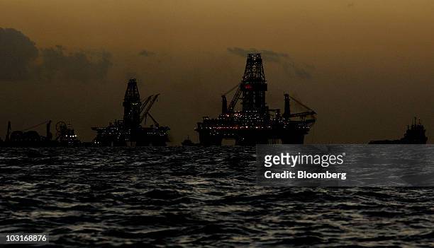 The Transocean Development Driller III and Transocean Development Driller II are silhouetted along with vessels leased by BP Plc after sunset at the...