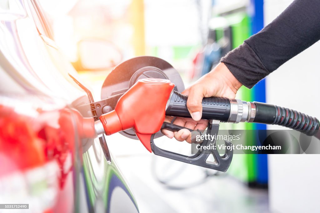 Car fuels concept, oil station hand and fuel nozzle in car