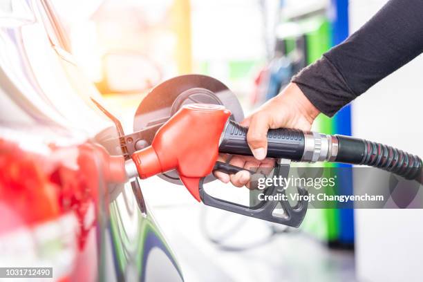 car fuels concept, oil station hand and fuel nozzle in car - tanque de combustível imagens e fotografias de stock