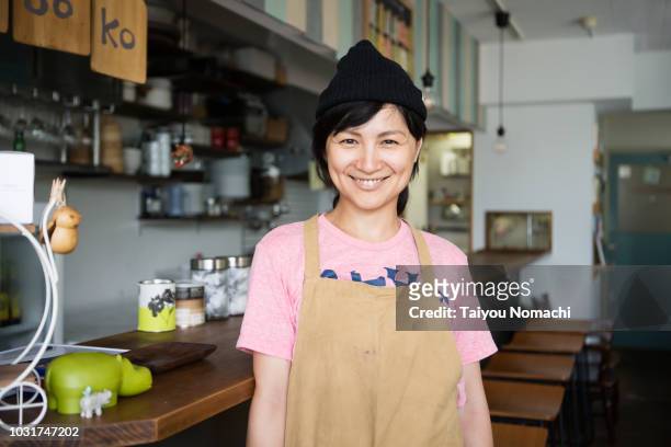 a woman owner who shows a proud smile in the kitchen - woman smile kitchen foto e immagini stock