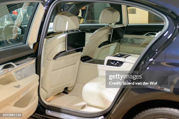 Interior on a BMW 7 series luxury limousine car. The car is fitted with leather seats, wood details and a large information display on the dahsboard....