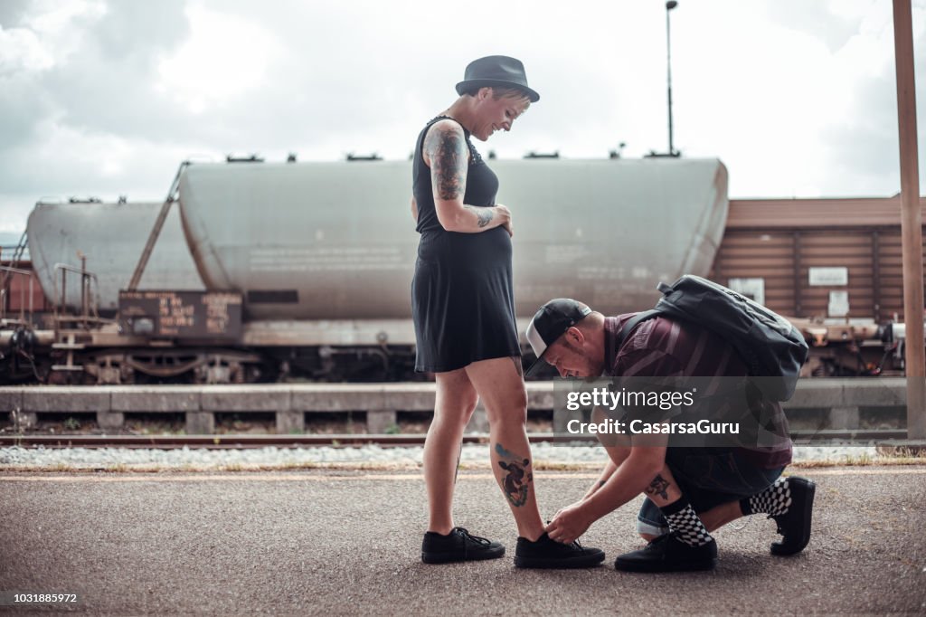 Young Man Tying Shoelaces For His Pregnant Girlfriend