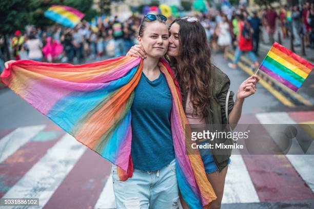 coppia femminile felice che si abbraccia e si bacia alla parata del gay pride - dimostrazione di protesta foto e immagini stock