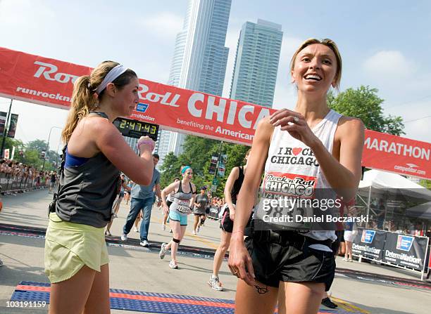 Kelli Zink and Giuliana Rancic rest after crossing the finish line at the Rock 'n' Roll Chicago Half Marathon on August 1, 2010 in Chicago, Illinois.