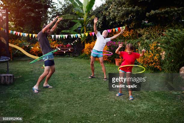 multi generation family hula hooping in backyard - jogar ao arco imagens e fotografias de stock
