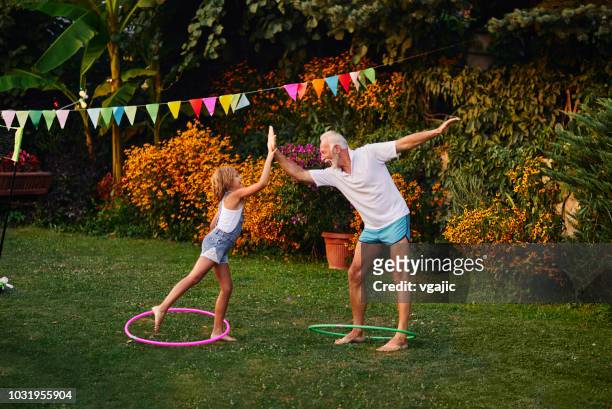 multi generatie familie hula hooping in achtertuin - hoelahoep stockfoto's en -beelden