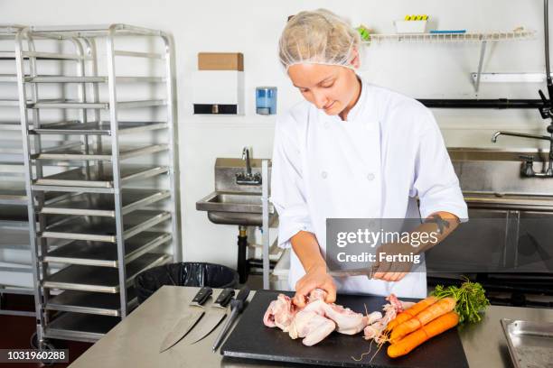 kontamination von lebensmitteln.  ein food-service arbeitnehmer schneiden rohem hühnerfleisch auf demselben brett neben rohem gemüse. - food safety stock-fotos und bilder