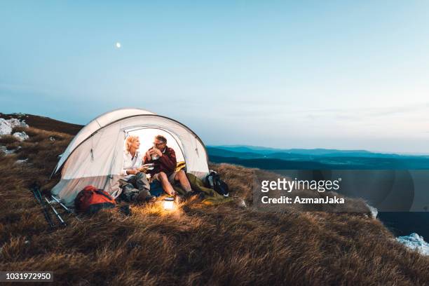coppia senior in campeggio in montagna e mangiare uno spuntino - camp foto e immagini stock