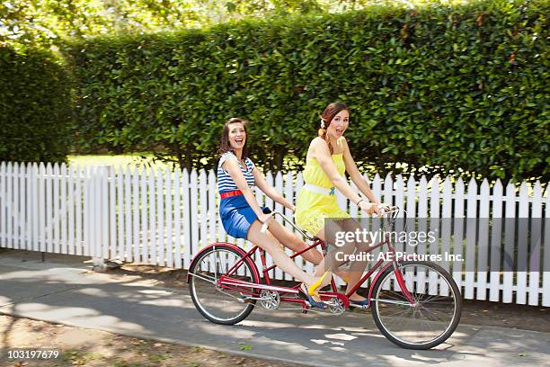 fashionable pair ride tandem bike - tandem stockfoto's en -beelden