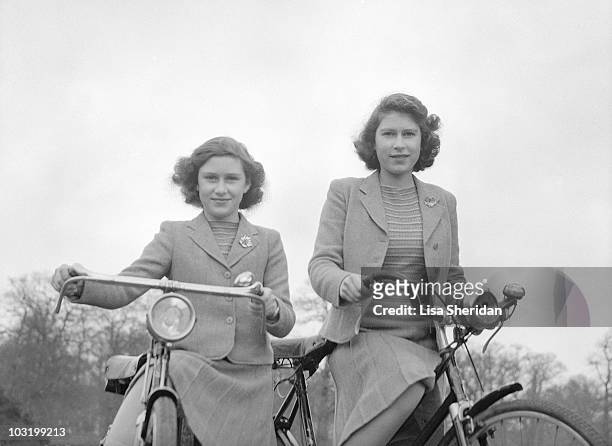 Princess Elizabeth and Princess Margaret pose on bicycles in Windsor, England on April 4, 1942.