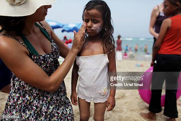 An Israeli woman rubs sunscreen on a Palestinian girl from the West Bank village of Jahalin as they spend the day at the beach on August 2, 2010 in...