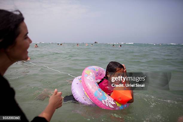 An Israeli woman plays with a Palestinian girl from the West Bank village of Jahalin, as they spend the day at the beach on August 2, 2010 in Bat...