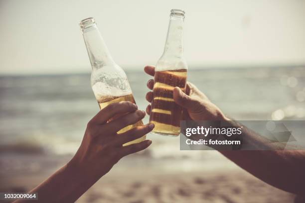 amis de grillage avec des bouteilles de bière à la plage - bouteille de bière photos et images de collection