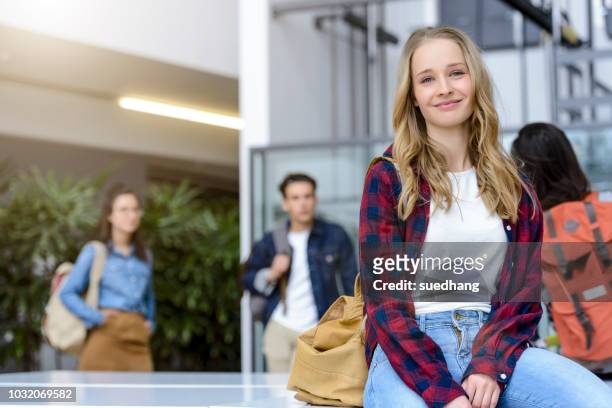 young female university student sitting in university lobby, portrait - student stock-fotos und bilder