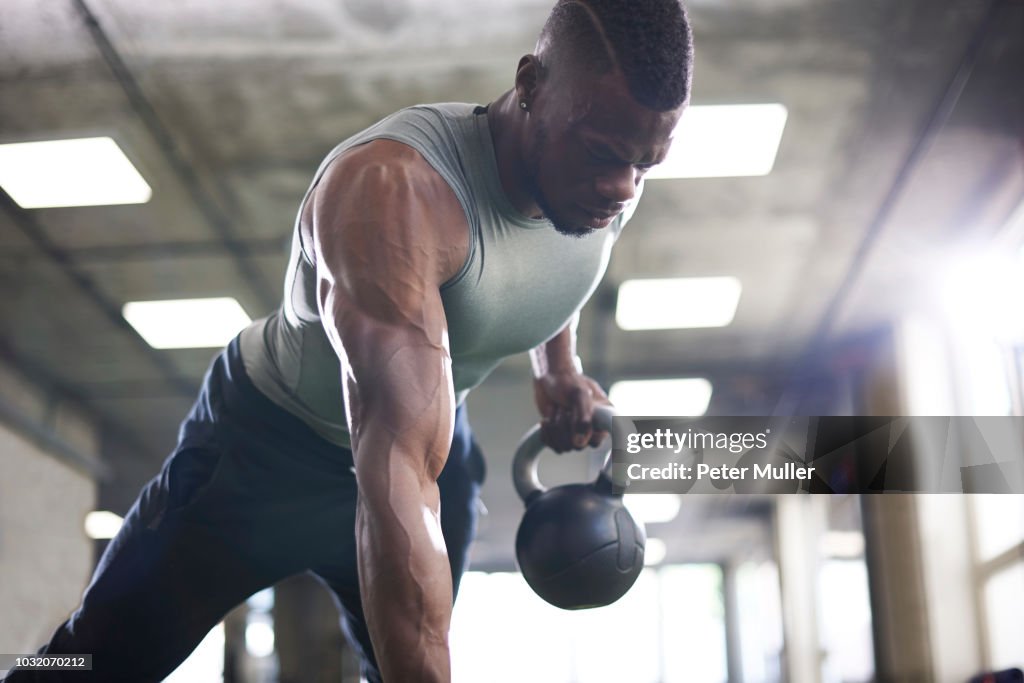 Man doing plank with kettlebells in gym