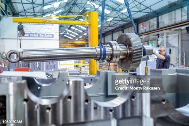 engineer using crane to position large gear with spindle in gearbox factory - engineer gearwheel factory stock pictures, royalty-free photos & images