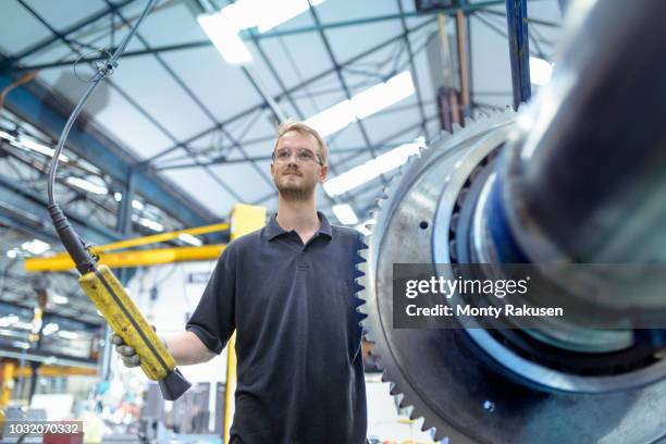 portrait of engineer with crane and large gear in gearbox factory - engineer gearwheel factory stockfoto's en -beelden