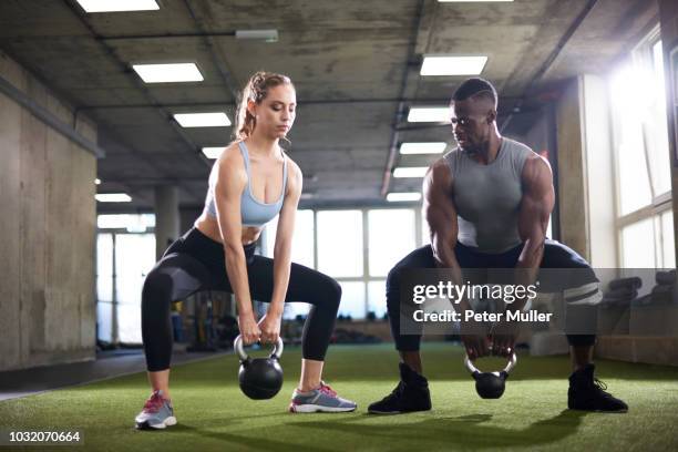 trainer and female client exercise with kettlebells in gym - woman straddling man stock pictures, royalty-free photos & images