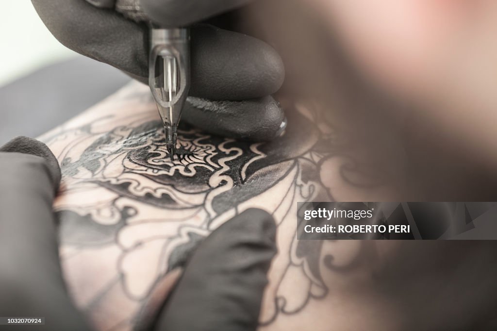 Tattooist drawing on arm of client