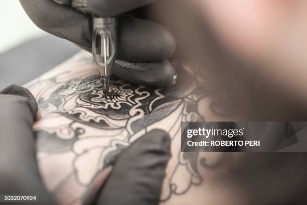 tattooist drawing on arm of client - tattoo gun tattoos stock pictures, royalty-free photos & images