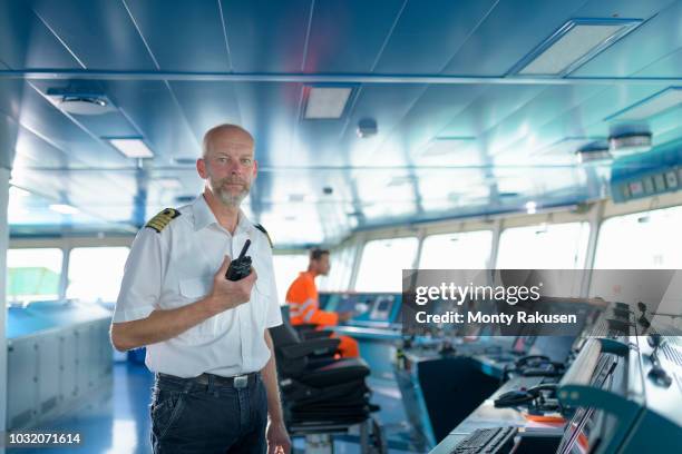 portrait of ship's captain on bridge onboard ship in port - capitaine de bateau photos et images de collection