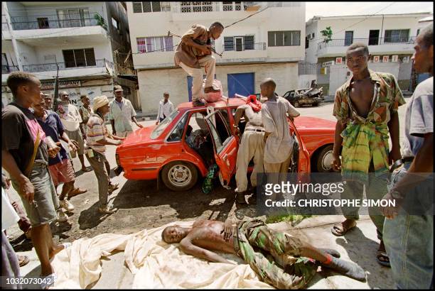 Liberian factional fighters prepare to remove the body of a comrade shot dead 12 May 1996 by ECOMOG peacekeeping troops after ignoring warnings to...