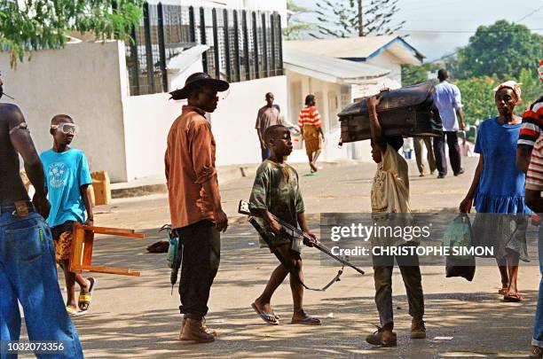 Armed with a rifle, a young boy stops a boy of his age, to check what he's carrying in his baggage, 14 April 1996 in Monrovia. Ten days after the...