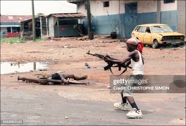 An eight-year-old boy, Kalashnikov gun in hand, loyal to the warlord Charles Taylor, chief of the National Patriotic Front of Liberia, leads a group...