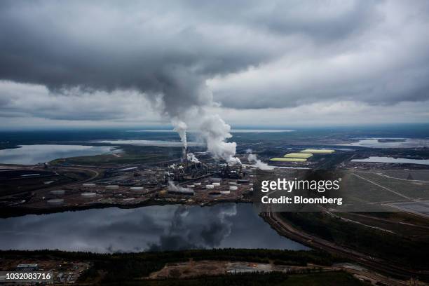 Steam rises from the Syncrude Canada Ltd. Upgrader plant in this aerial photograph taken above the Athabasca oil sands near Fort McMurray, Alberta,...