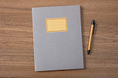 Grey school notebook or diary, old fashioned, on wooden desk, blank label, space for text, top view