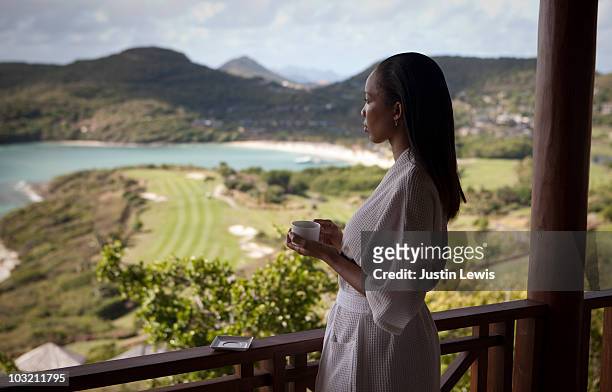 young woman on balcony overlooking resort midday - woman in bathrobe stock pictures, royalty-free photos & images