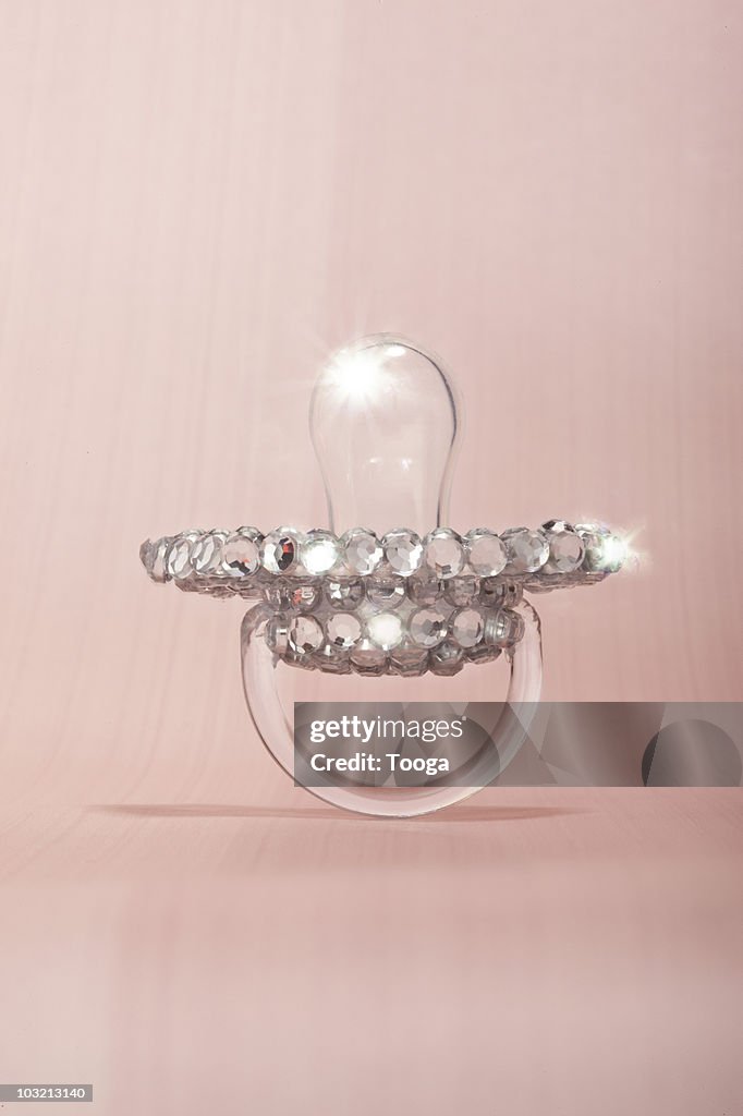 Baby pacifier covered in diamonds on pink