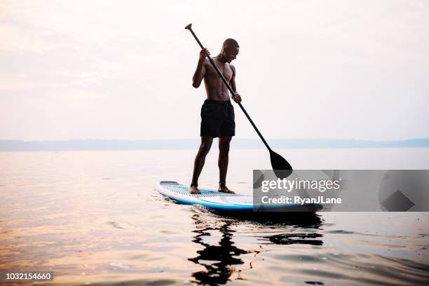 jovem adulto paddleboarding puget sound no verão - rep - fotografias e filmes do acervo