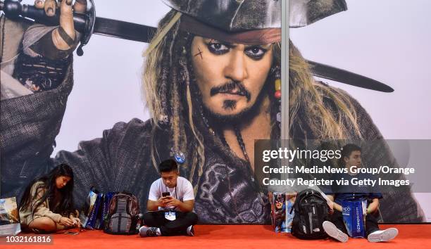 Andion Delmundo, left, Regan Delmundo, center, and Jeff Li rela under the watchful eye of Captain Jack Sparrow during the D23 Expo at the Anaheim...