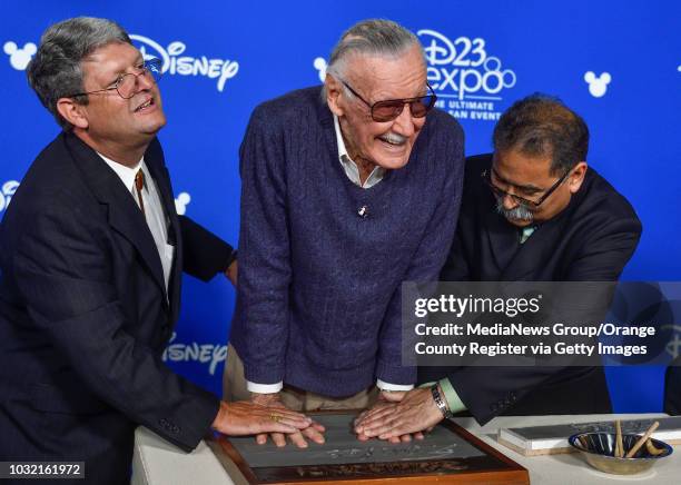 Marvel co-creator Stan Lee gets some help putting his hands in cement after after accepting a Disney Legend Award during a ceremony at D23 Expo in...