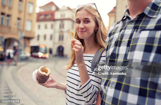 woman enjoying the street food with boyfriend - holding trdelnik (traditional czech hot sweet pastry) - trdelník stock pictures, royalty-free photos & images