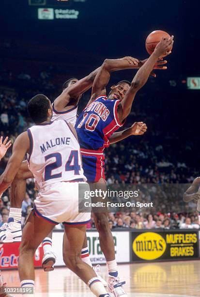 Dennis Rodman of the Detroit Pistons pulls down a rebound in front of Jeff Malone of the Washington Bullets circa 1988 during an NBA basketball game...