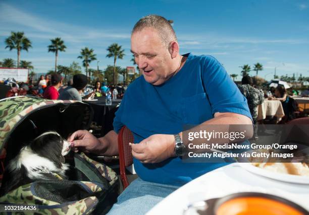 Randy Cormier, of Anaheim feeds his dog Chim Chim while enjoying a Thanksgiving dinner during the annual We Give Thanks event at Honda Center...