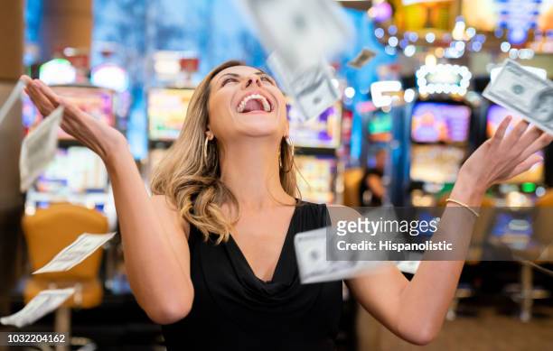 cheerful beautiful woman excited about all the money she won at the casino throwing to the air - casino stock pictures, royalty-free photos & images